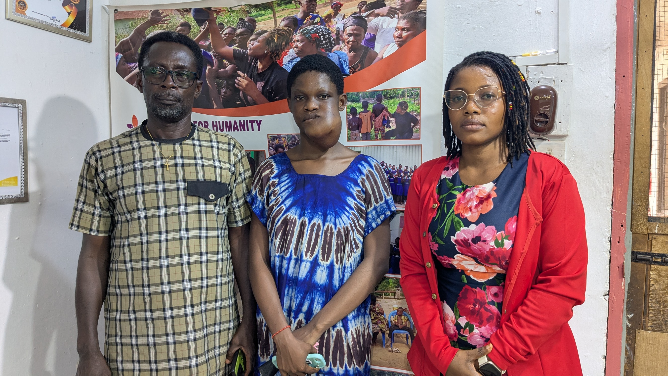 Members of the Passion for Humanity Ghana team posing in front of their office banner