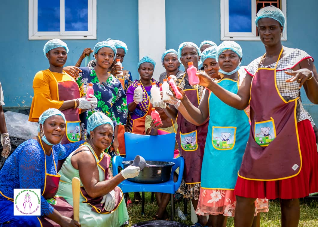 Group of women holding handmade soap bottles after a livelihood training