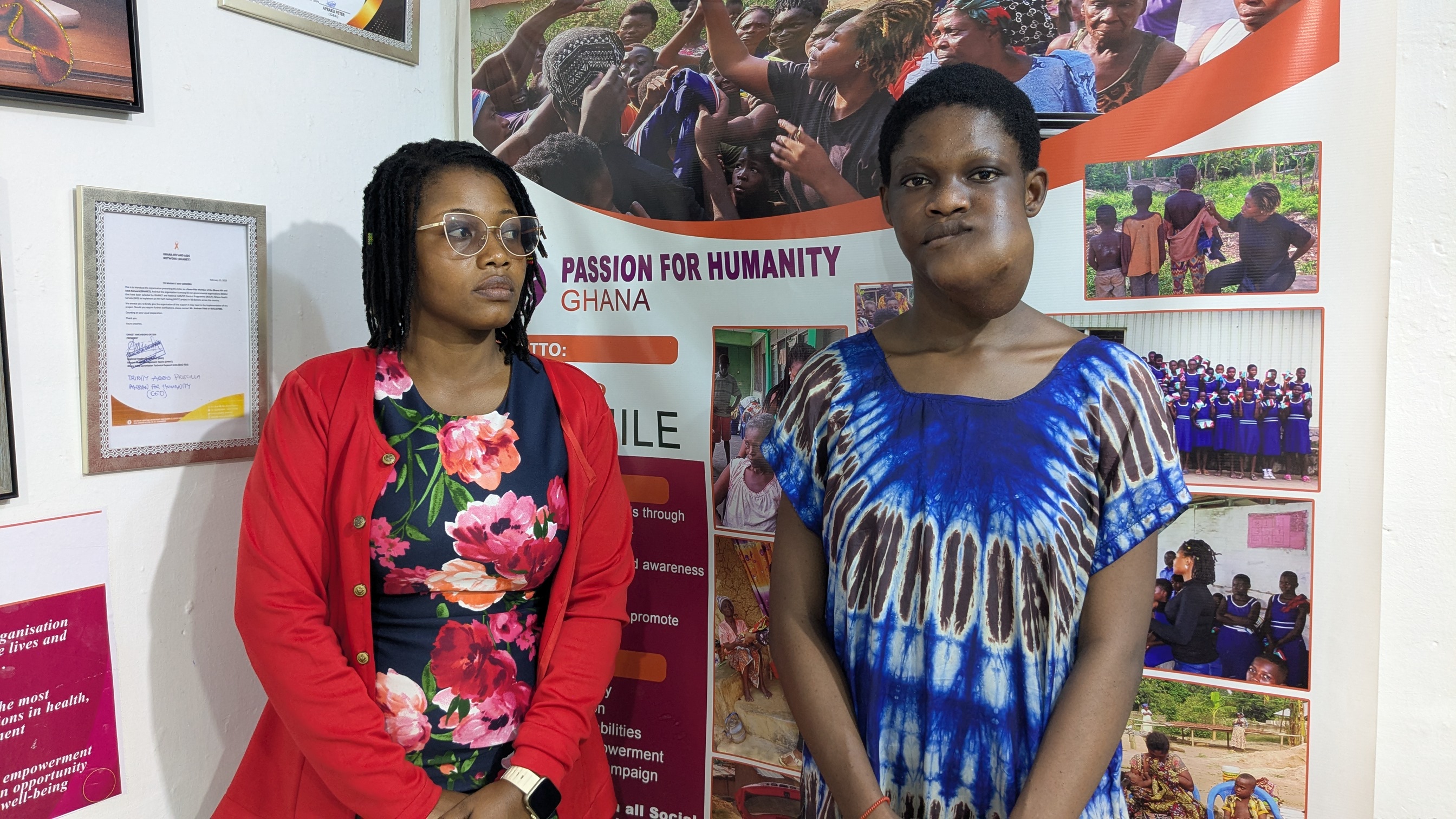 Two Passion for Humanity Ghana team members in front of the office banner