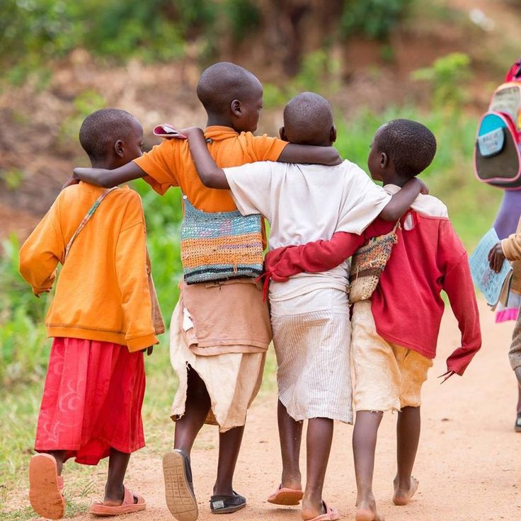 Four children walking arm in arm down a village road