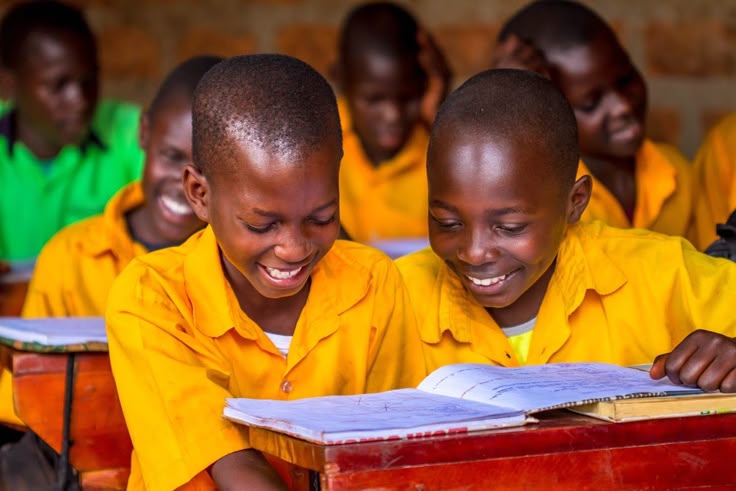 Two boys in yellow uniforms reading together in a Ghanaian classroom